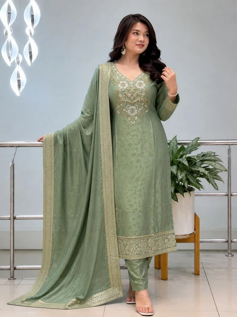 Woman wearing a green traditional outfit with a matching dupatta in an indoor setting.