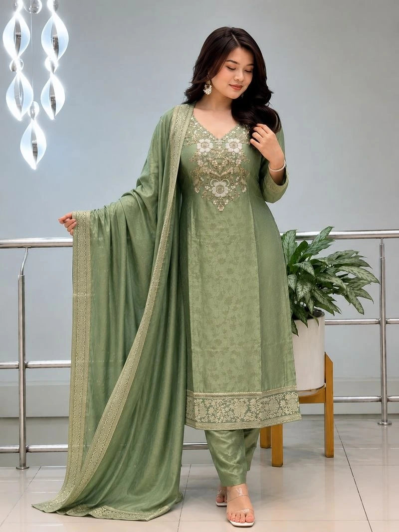 Woman wearing a green traditional outfit with embroidery in an indoor setting.