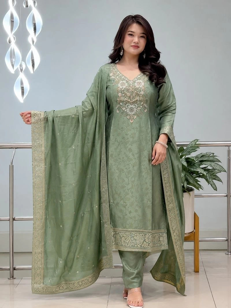 Woman wearing a green traditional outfit with embroidery indoors.