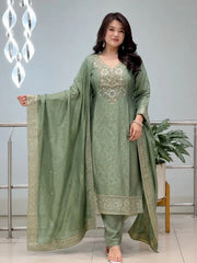 Woman wearing a green traditional outfit with embroidery indoors.