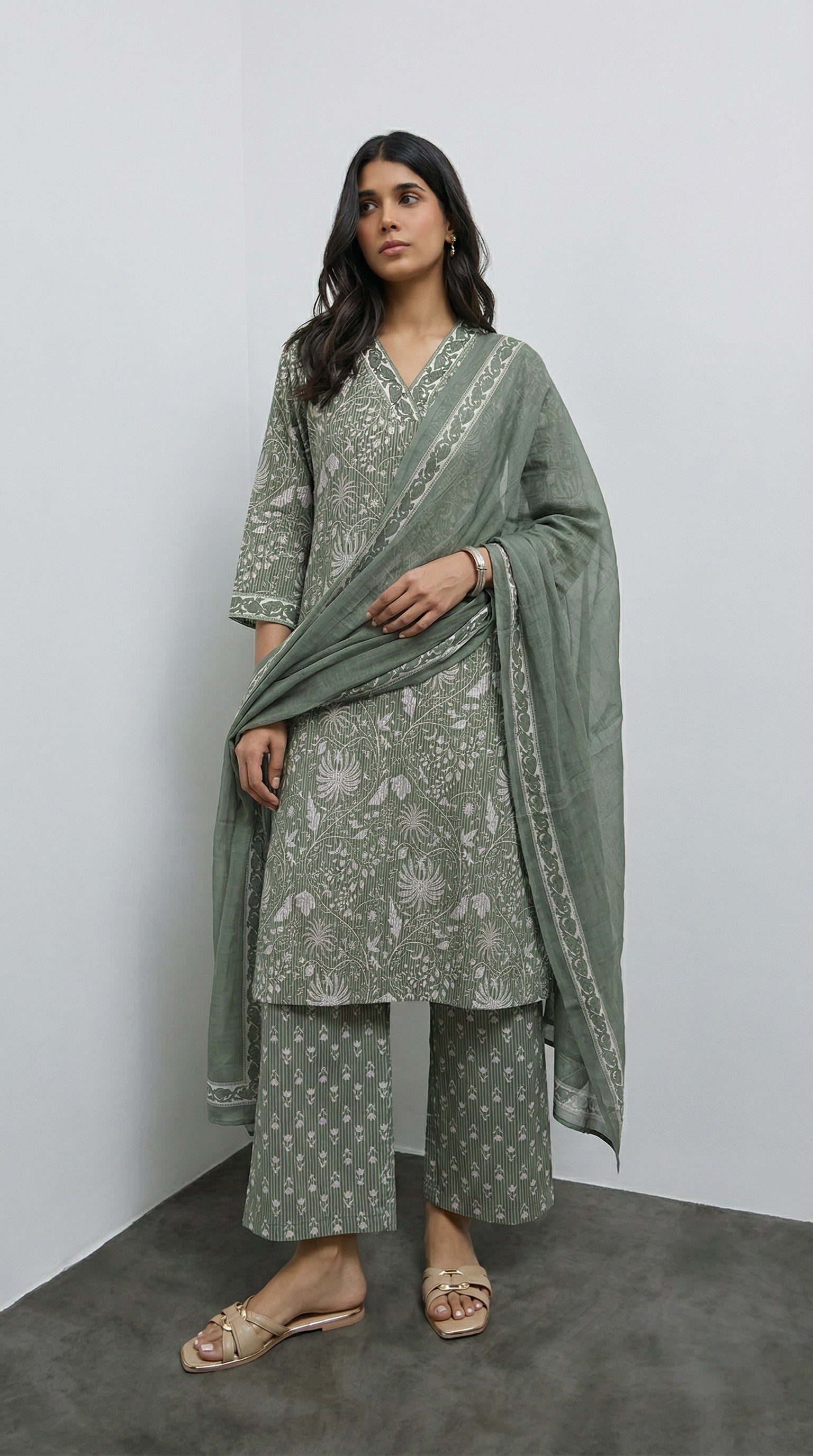 Woman wearing a green traditional outfit with a matching dupatta against a white background