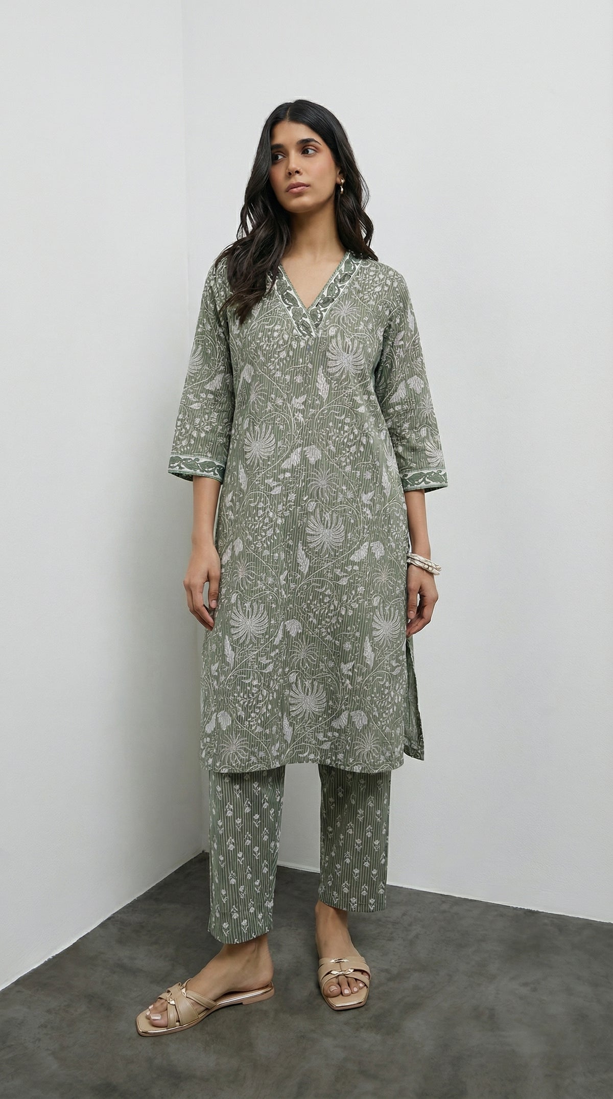 Woman wearing a green patterned kurta with pants against a white background