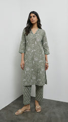 Woman wearing a green patterned kurta with pants against a white background