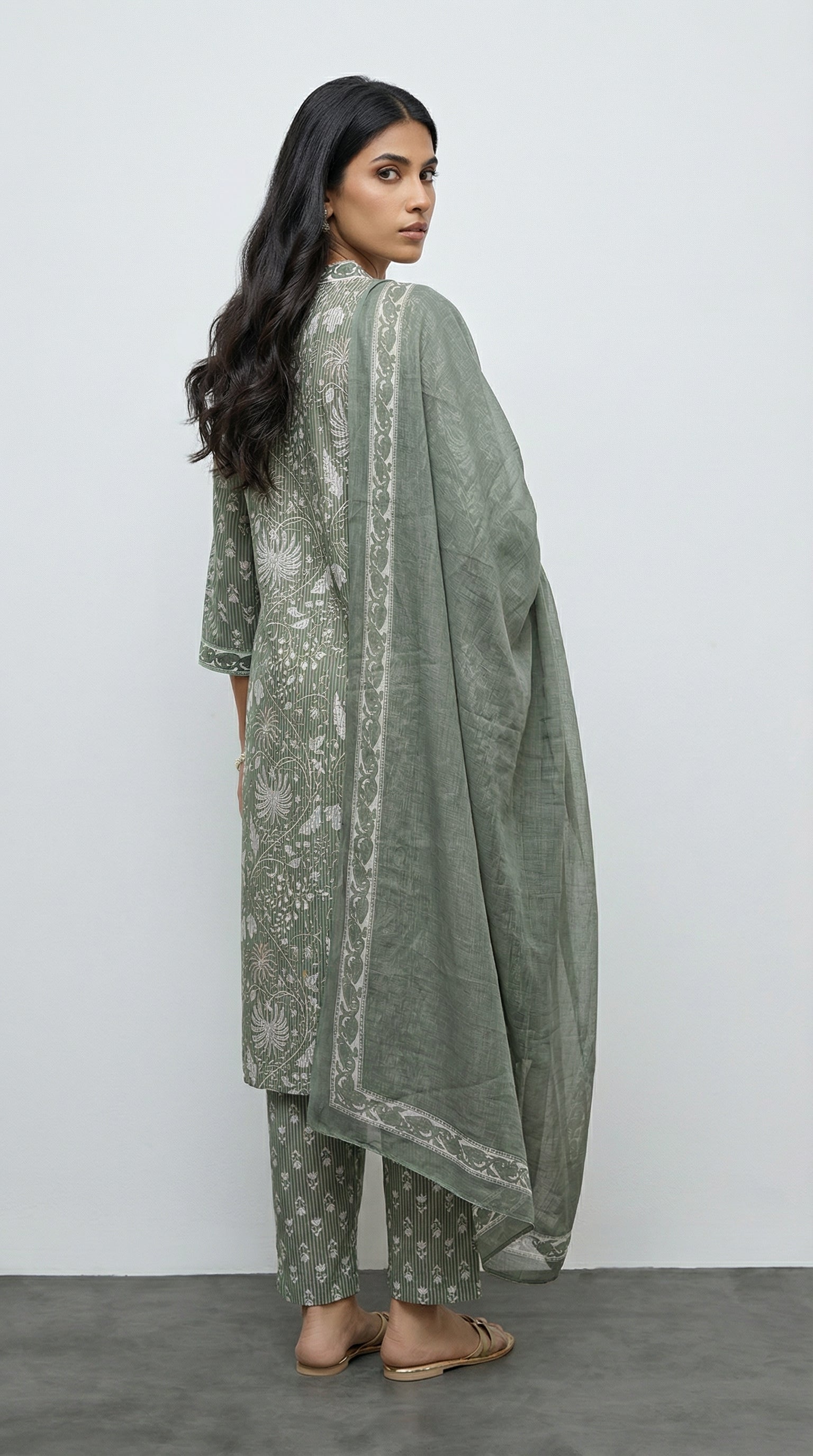 Woman wearing a green traditional outfit with a plain background