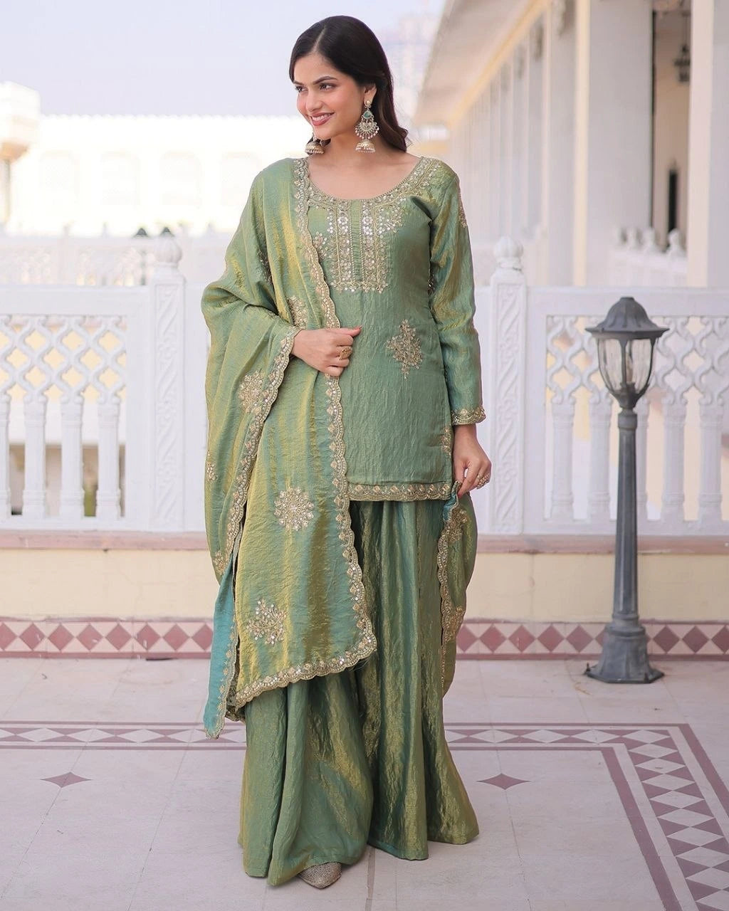 Woman in a green traditional outfit standing on a decorative floor.