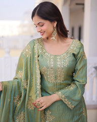 Woman wearing a green embroidered traditional outfit with a blurred indoor background