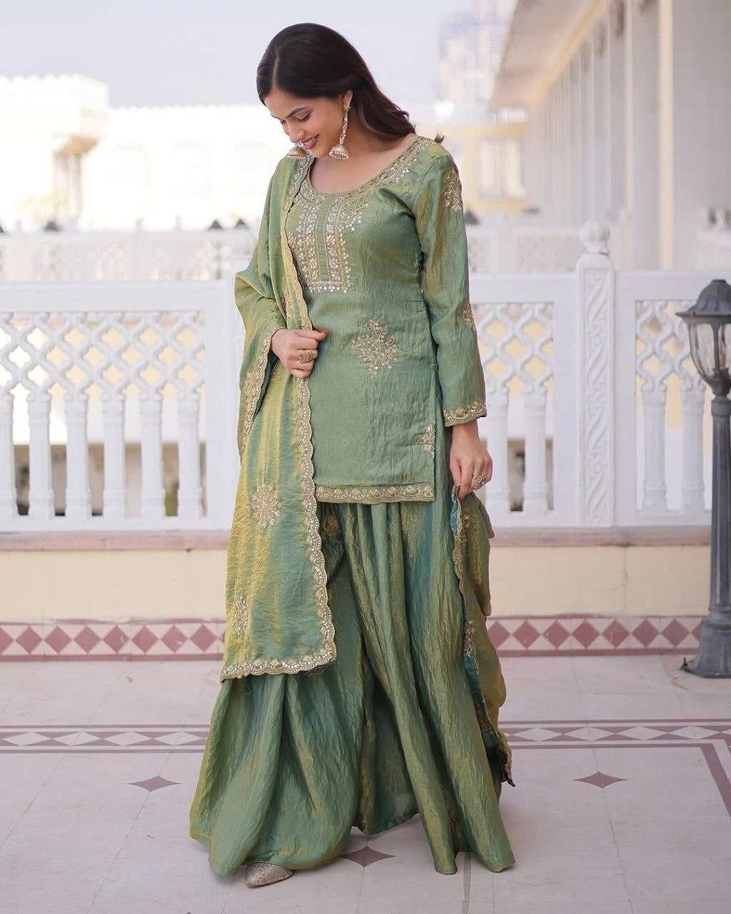Woman in a green traditional outfit standing on a balcony.