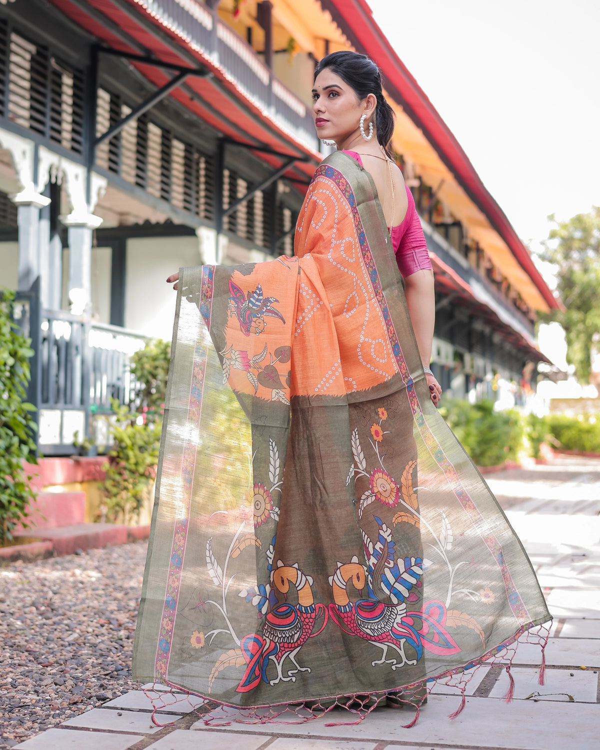 Woman in traditional attire with a colorful dupatta in front of a building.