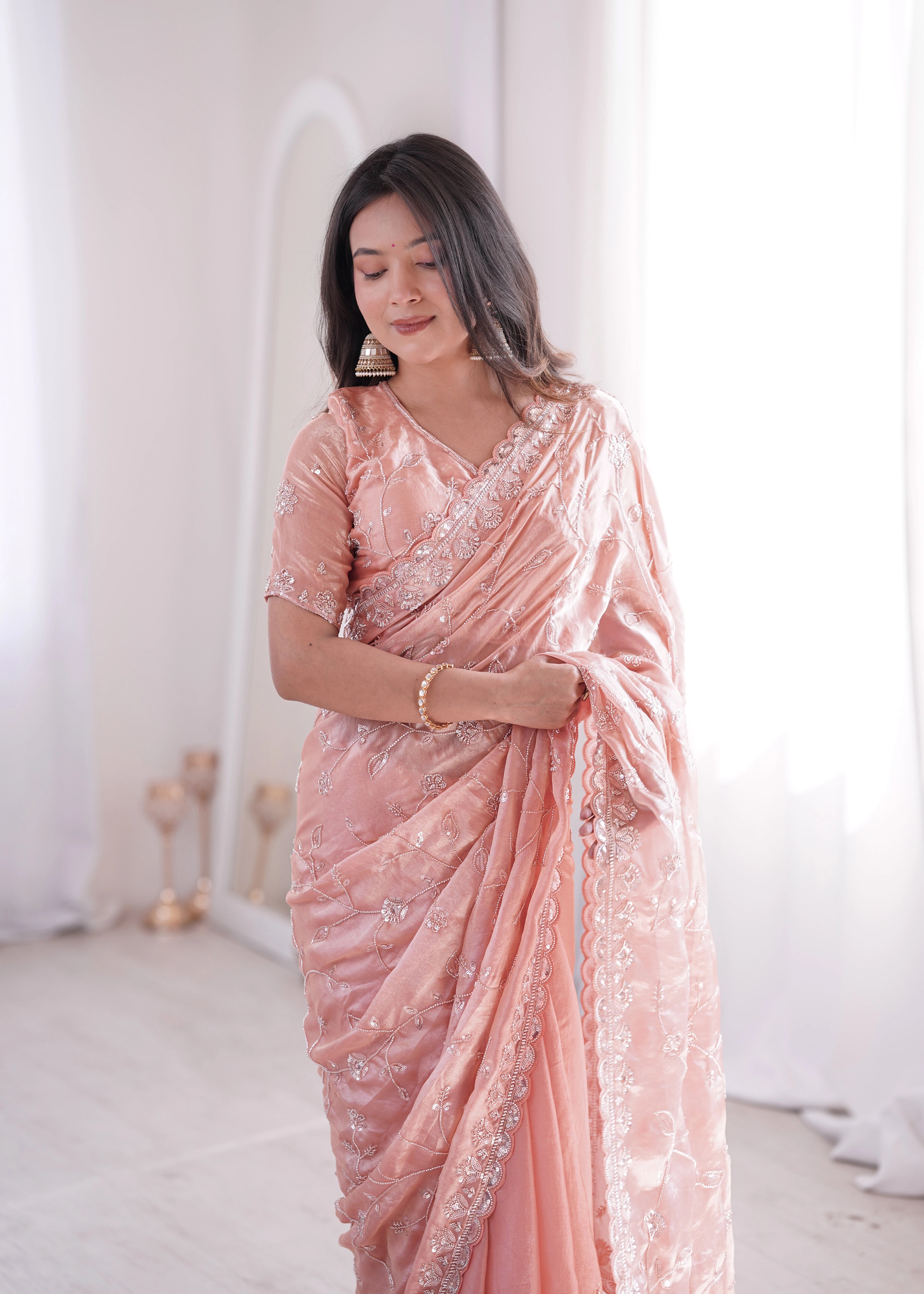 Woman wearing a pink saree with white patterns in a minimalistic setting