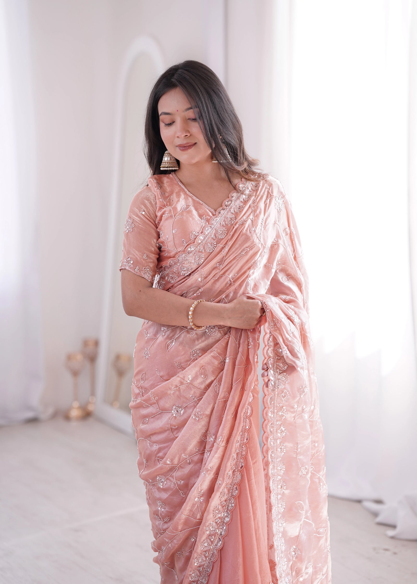 Woman wearing a pink saree with white patterns in a minimalistic setting