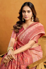 Woman in a pink saree sitting on a wooden chair against an orange background