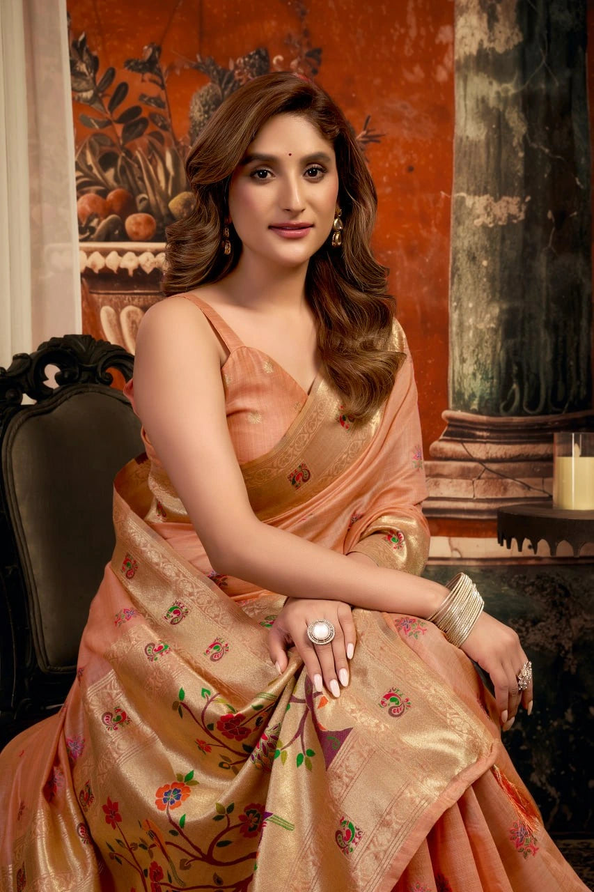 Woman in a peach saree sitting in an elegant indoor setting
