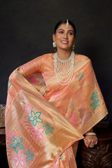 Woman wearing a peach saree with floral patterns against a dark background