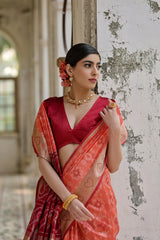 Woman in a red and orange saree with floral earrings in an indoor setting