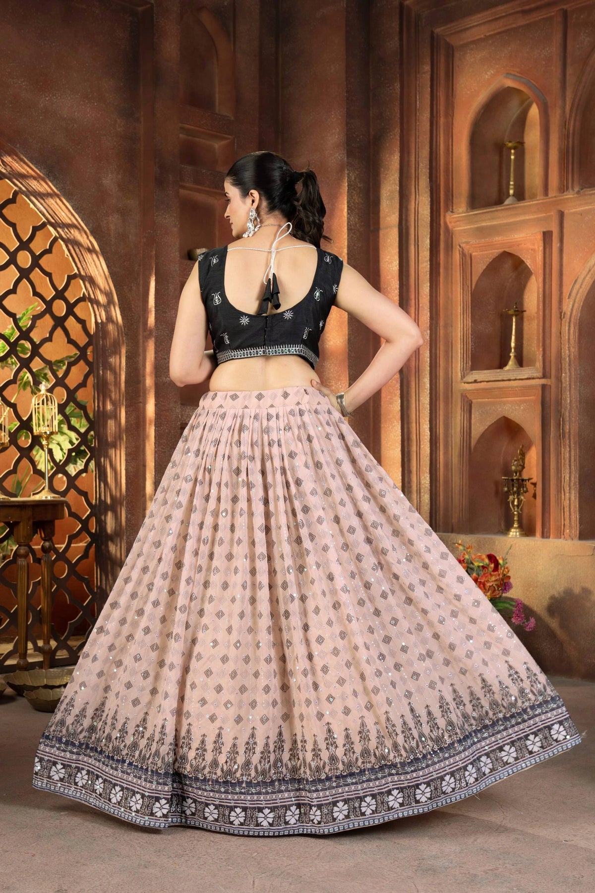 Woman in a traditional outfit with a dark top and light skirt in an ornate indoor setting.