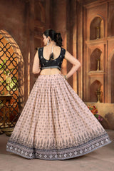 Woman in a traditional outfit with a dark top and light skirt in an ornate indoor setting.