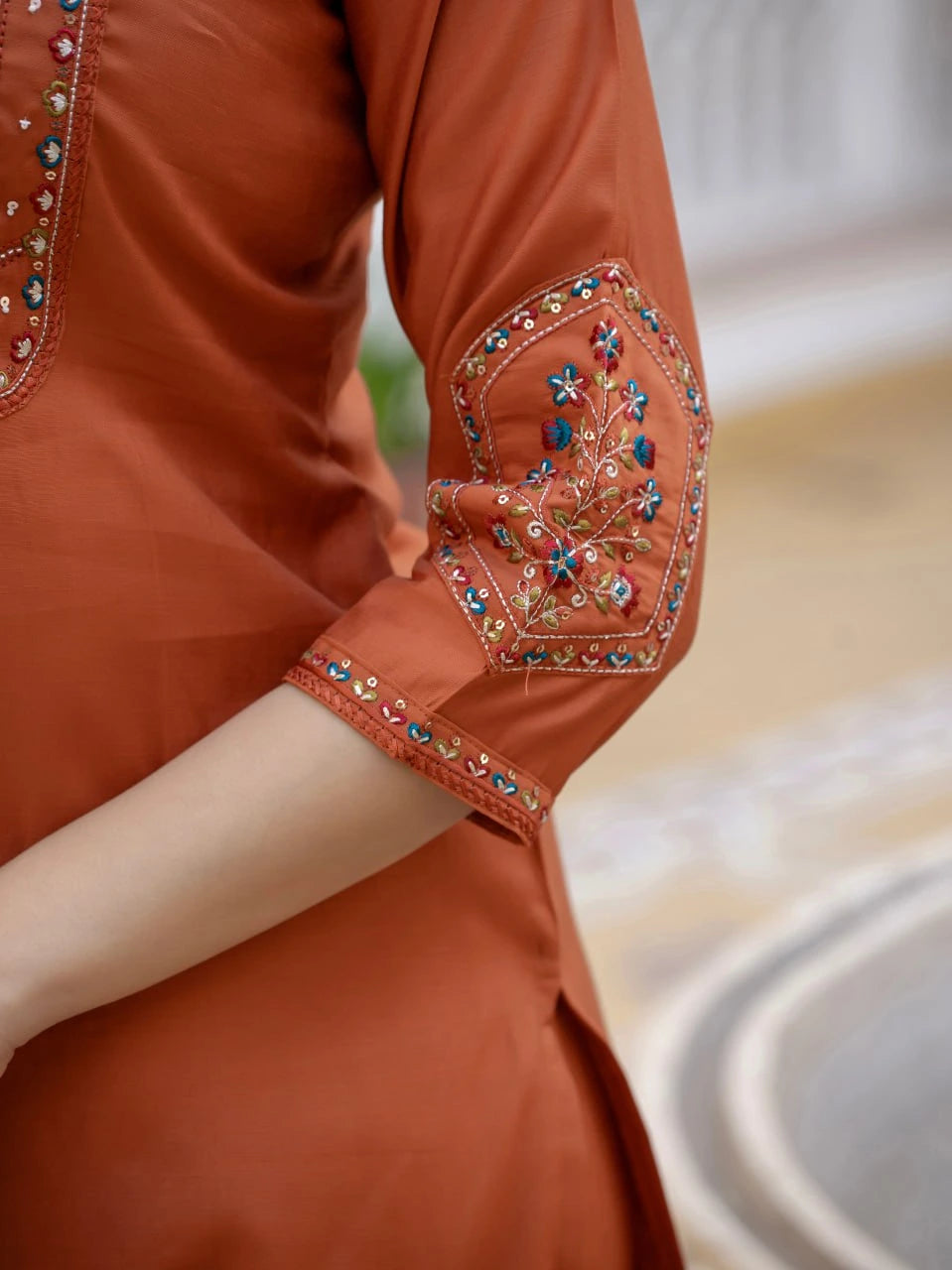 Brown embroidered garment with intricate designs on a blurred background