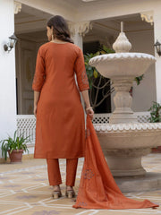 Woman in an orange traditional outfit standing in a decorative outdoor setting.