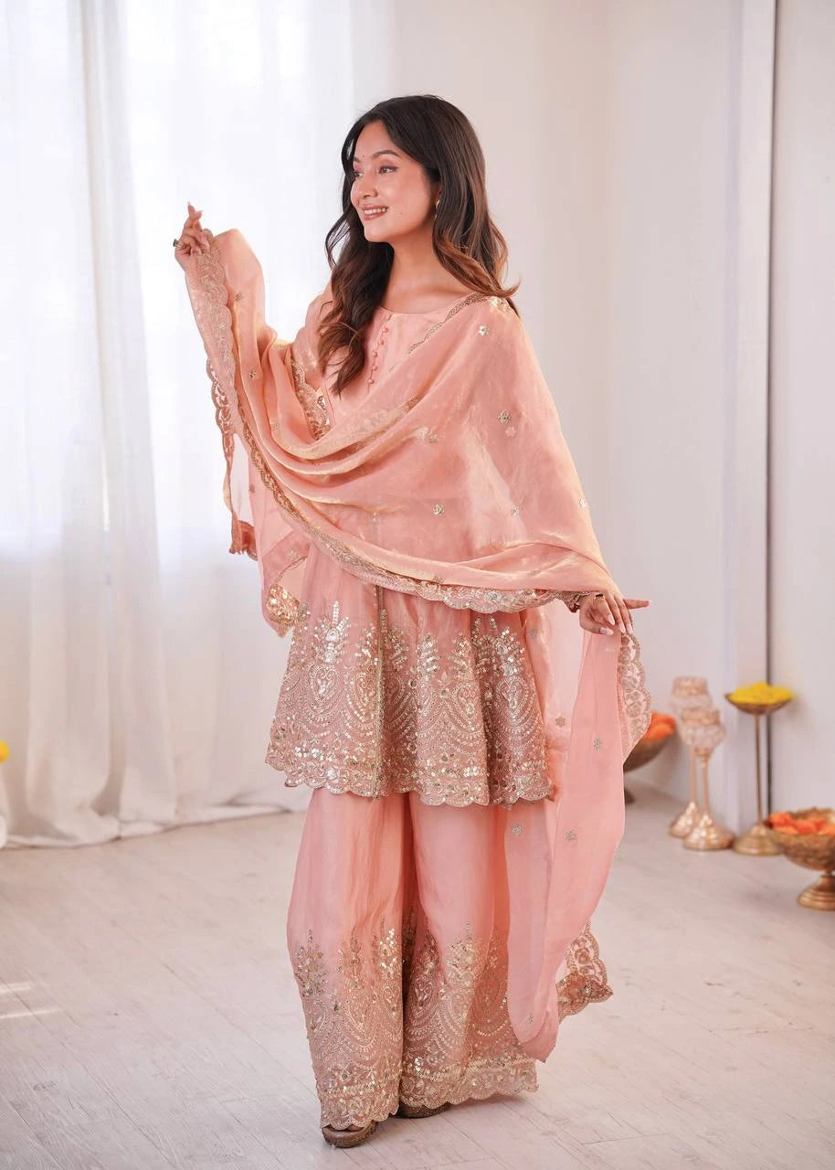 Woman in a traditional pink and gold outfit with a white curtain background