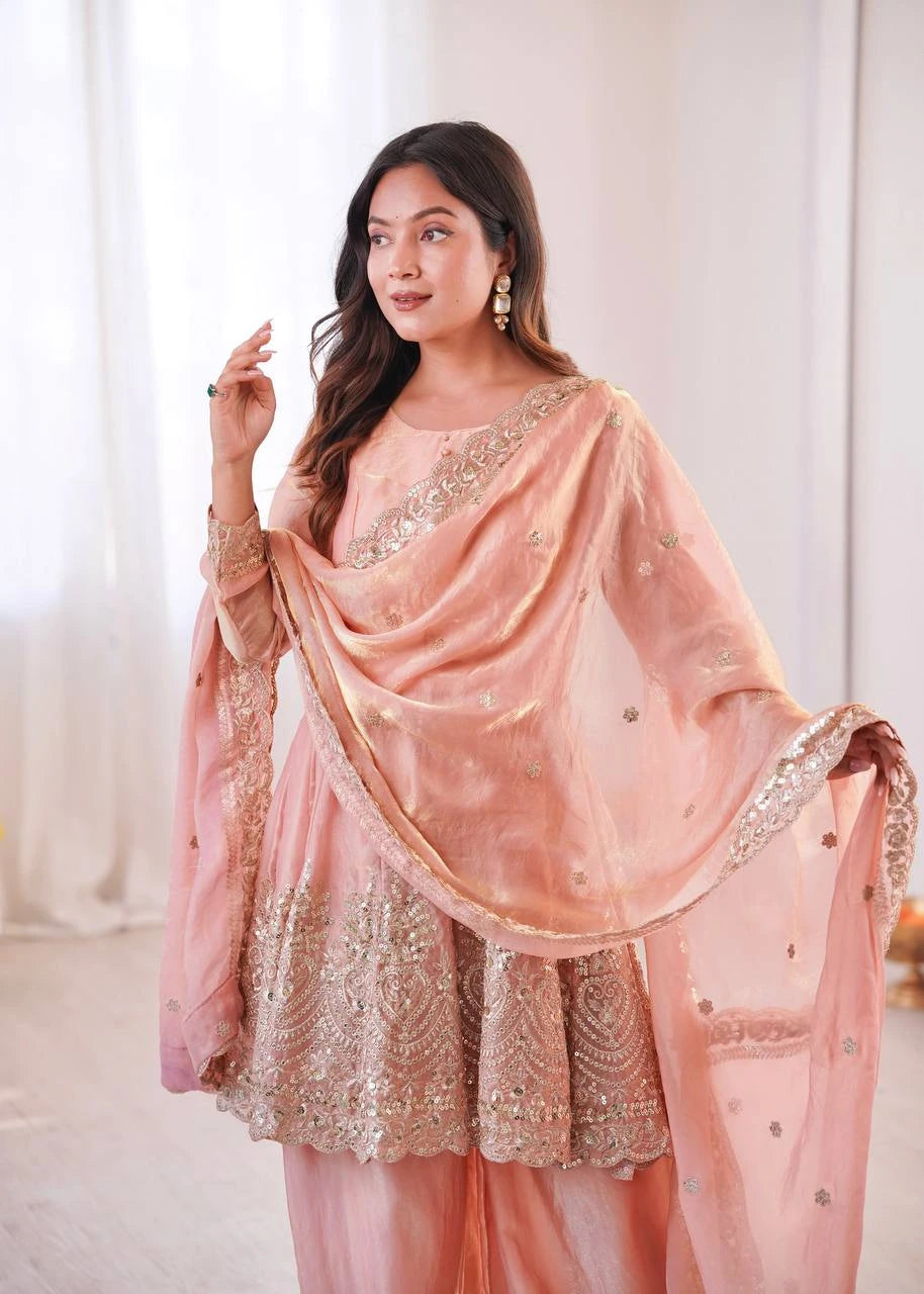 Woman wearing a peach embroidered traditional outfit with a matching dupatta.