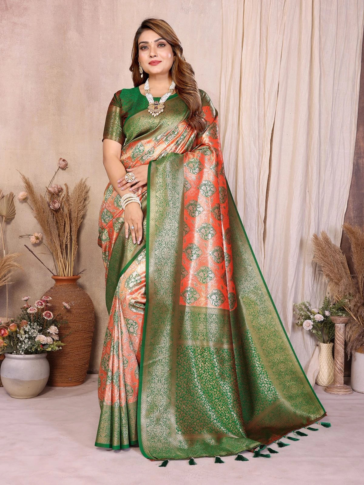 Woman wearing a green and orange saree with a neutral background