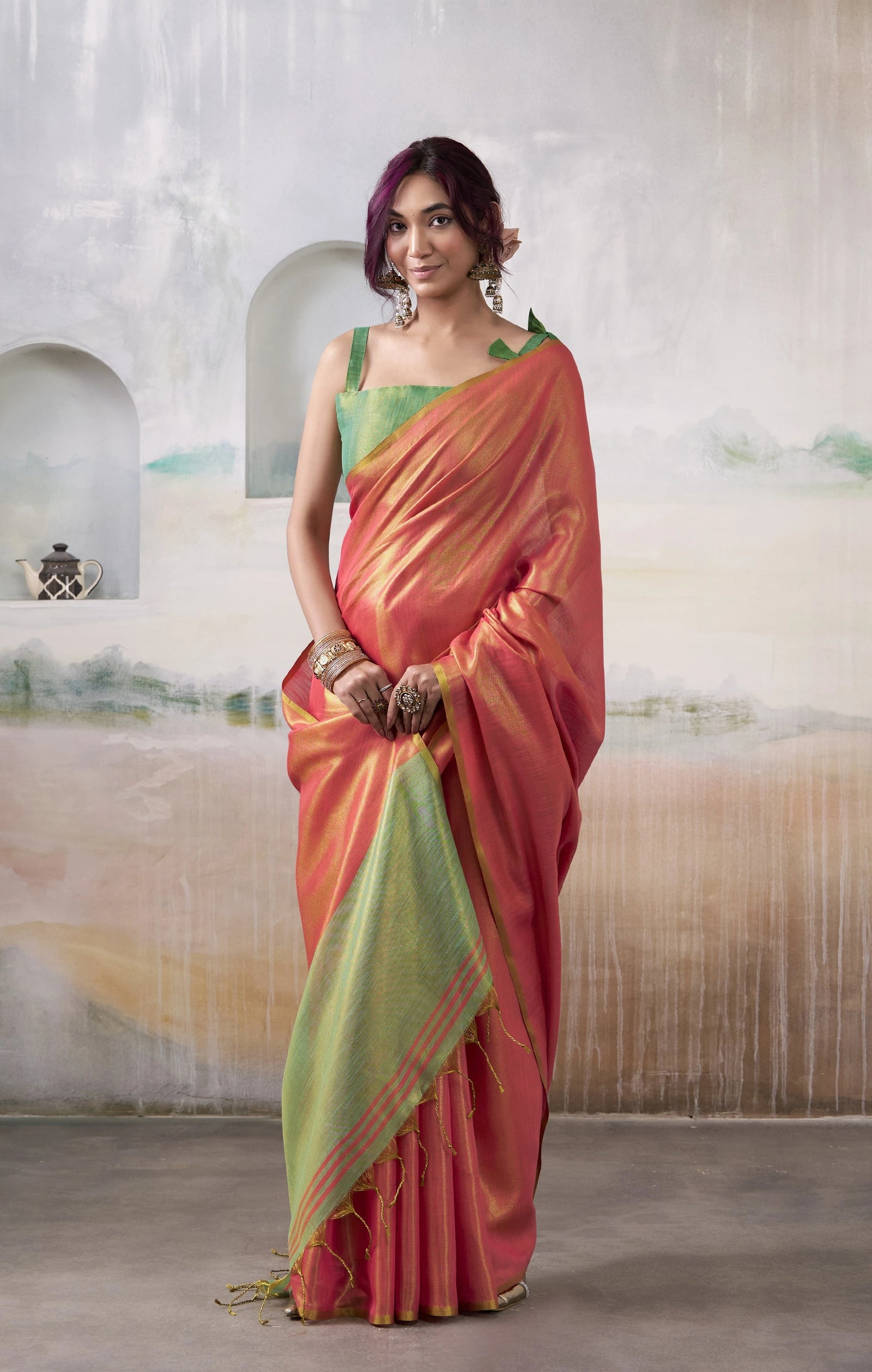 Woman wearing a red and green saree with a neutral background