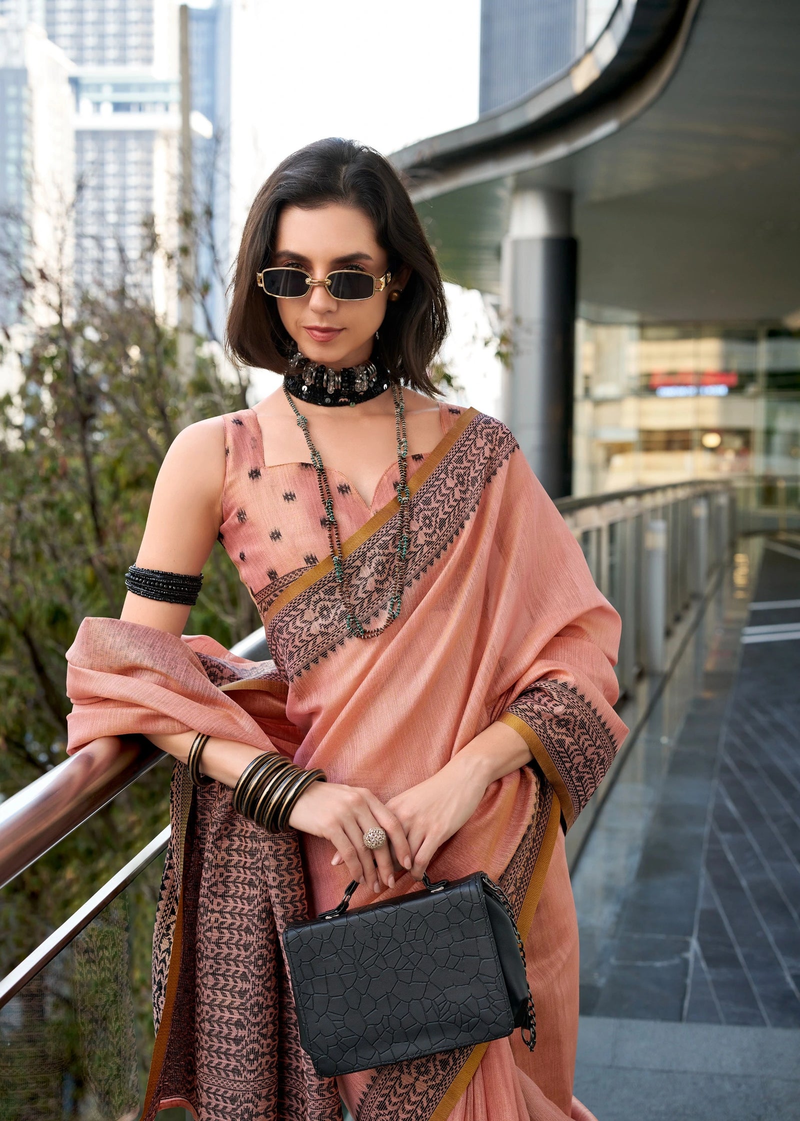 Woman in a traditional outfit with sunglasses and a black handbag in an urban setting