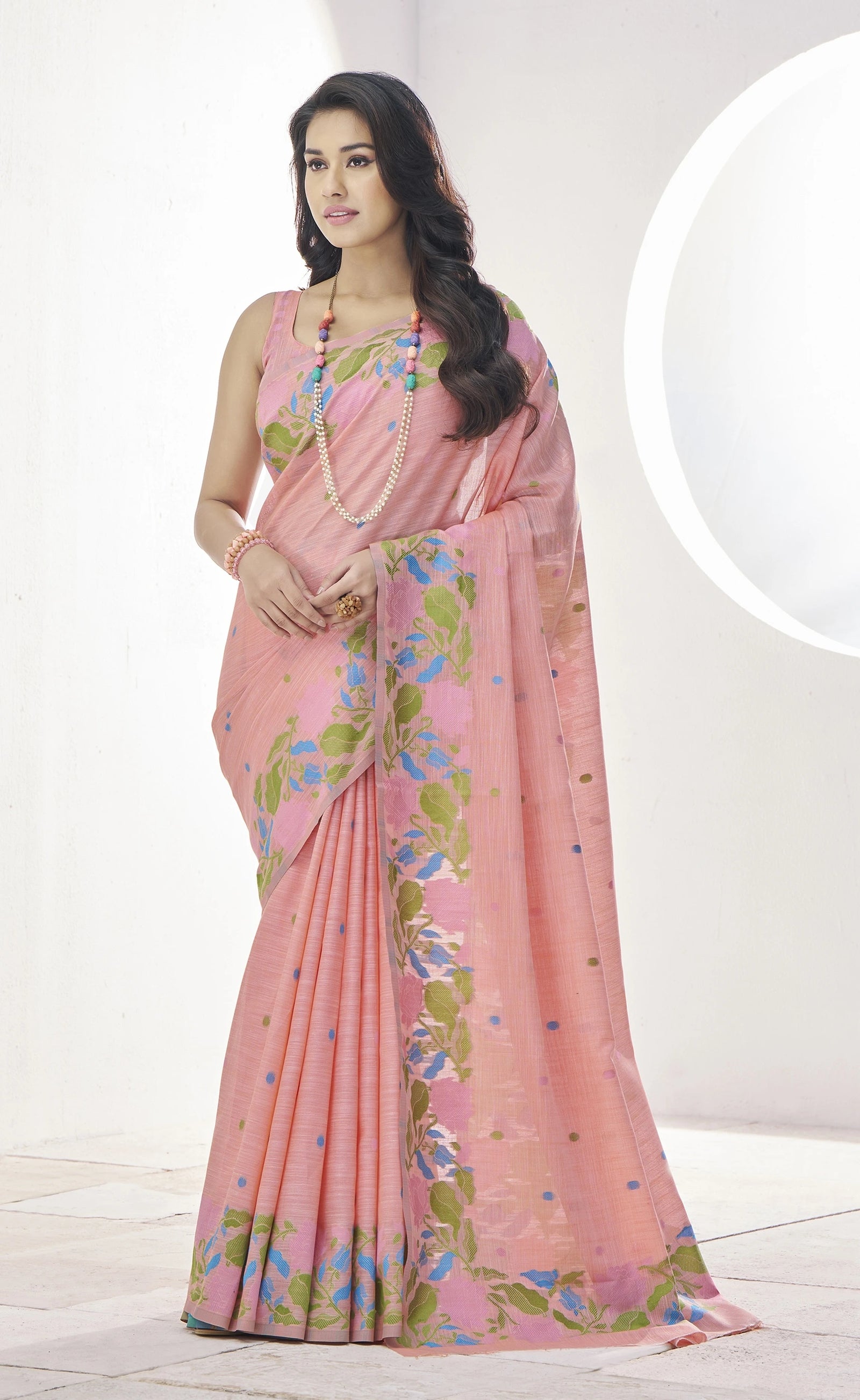 Woman wearing a pink saree with floral patterns on a white background