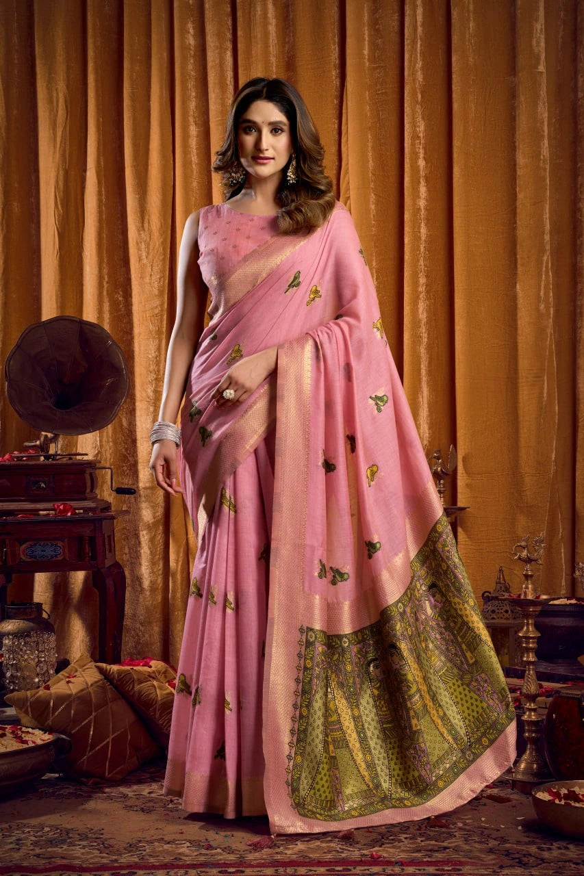 Woman in a pink saree with green border standing in an ornate room.