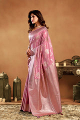 Woman wearing a pink saree in an indoor setting with decorative elements.
