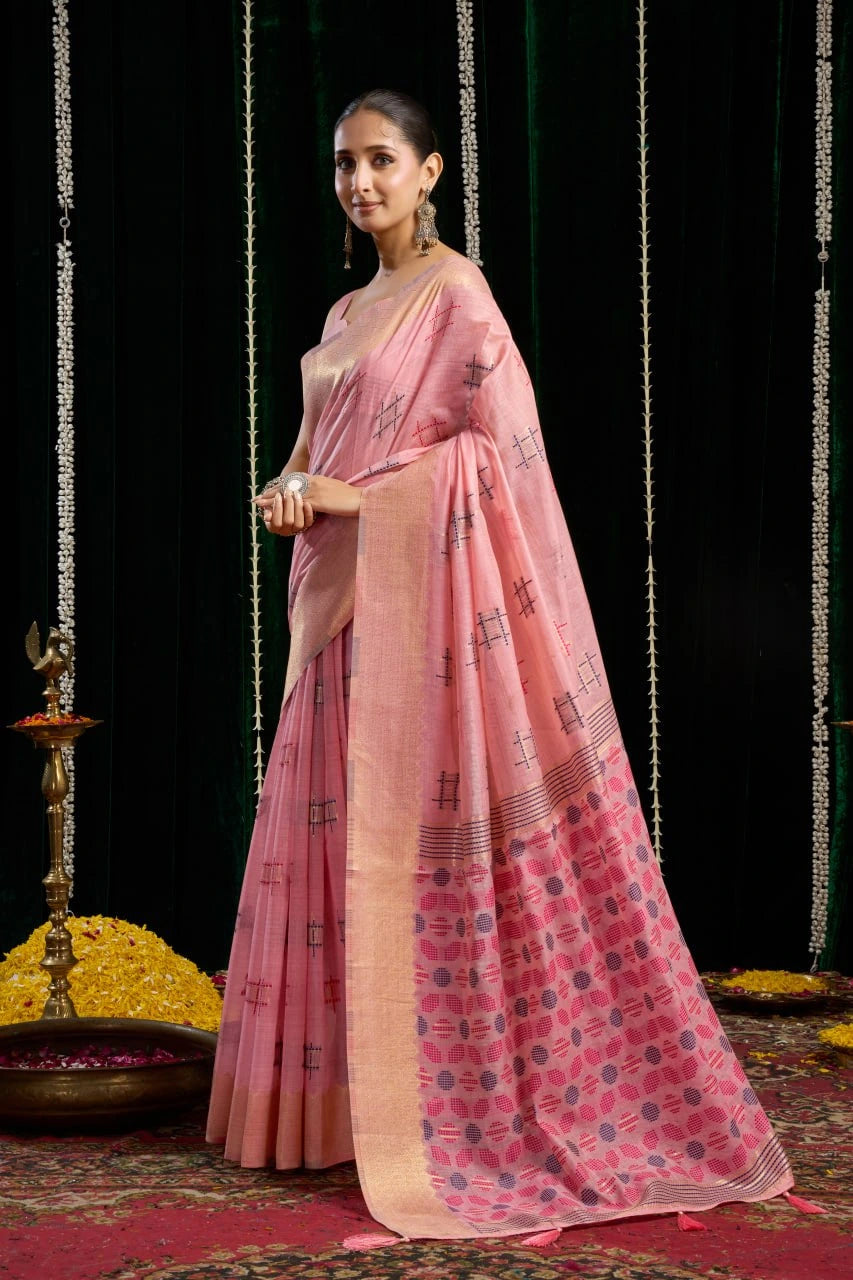 Woman in a pink saree standing against a dark background with decorative elements.