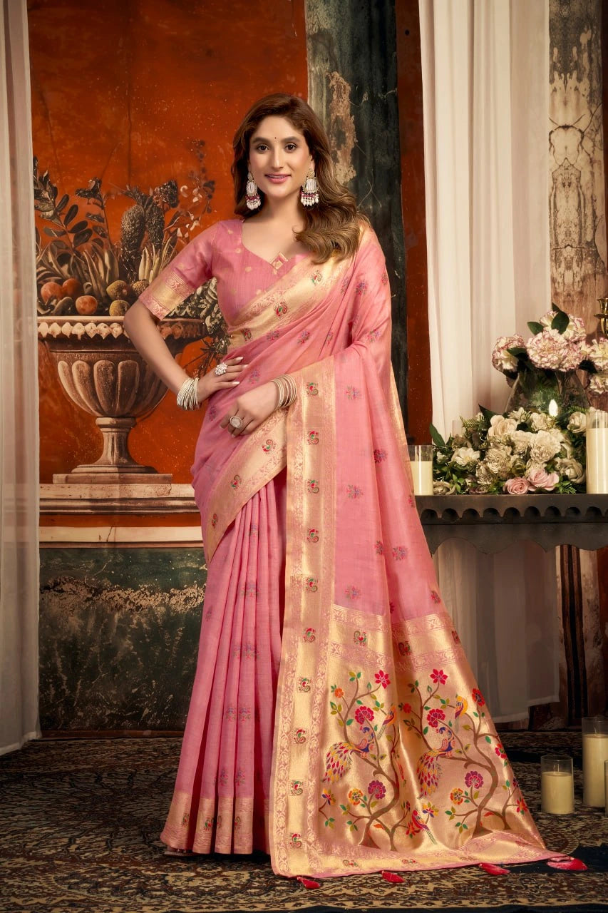 Woman in a pink saree with floral patterns in an elegant indoor setting.