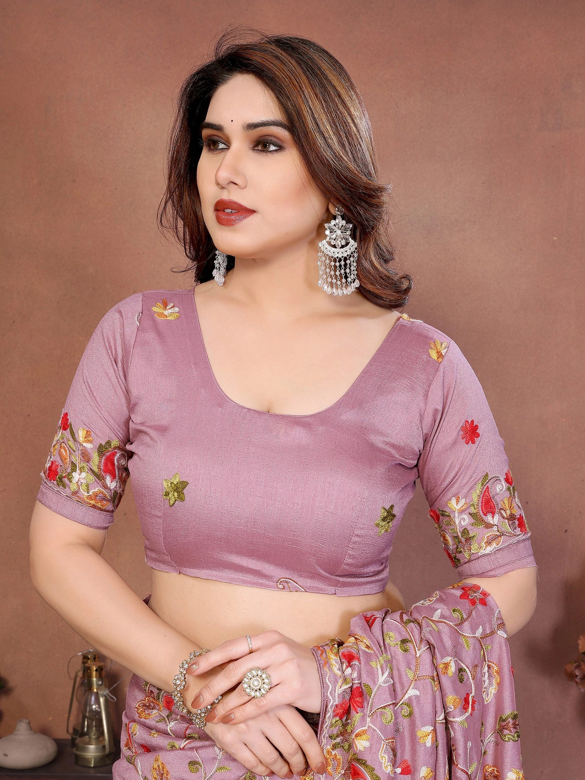 Woman wearing a purple saree with floral patterns on a brown background