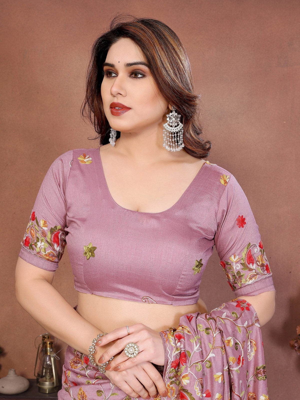 Woman wearing a purple saree with floral patterns on a brown background