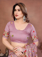 Woman wearing a purple saree with floral patterns on a brown background