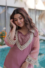 Woman wearing a pink traditional outfit with intricate designs by a poolside.