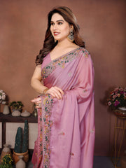 Woman wearing a pink saree with intricate designs against a brown background