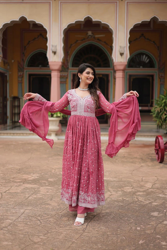 Woman in a pink traditional outfit standing in front of an architectural building.