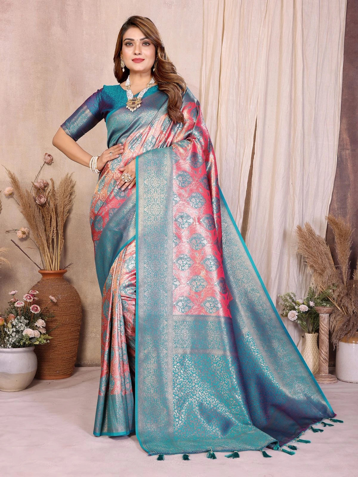 Woman wearing a blue and pink saree with a decorative border in a room setting.