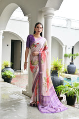 Woman in a floral saree standing in an outdoor setting with white columns and plants.