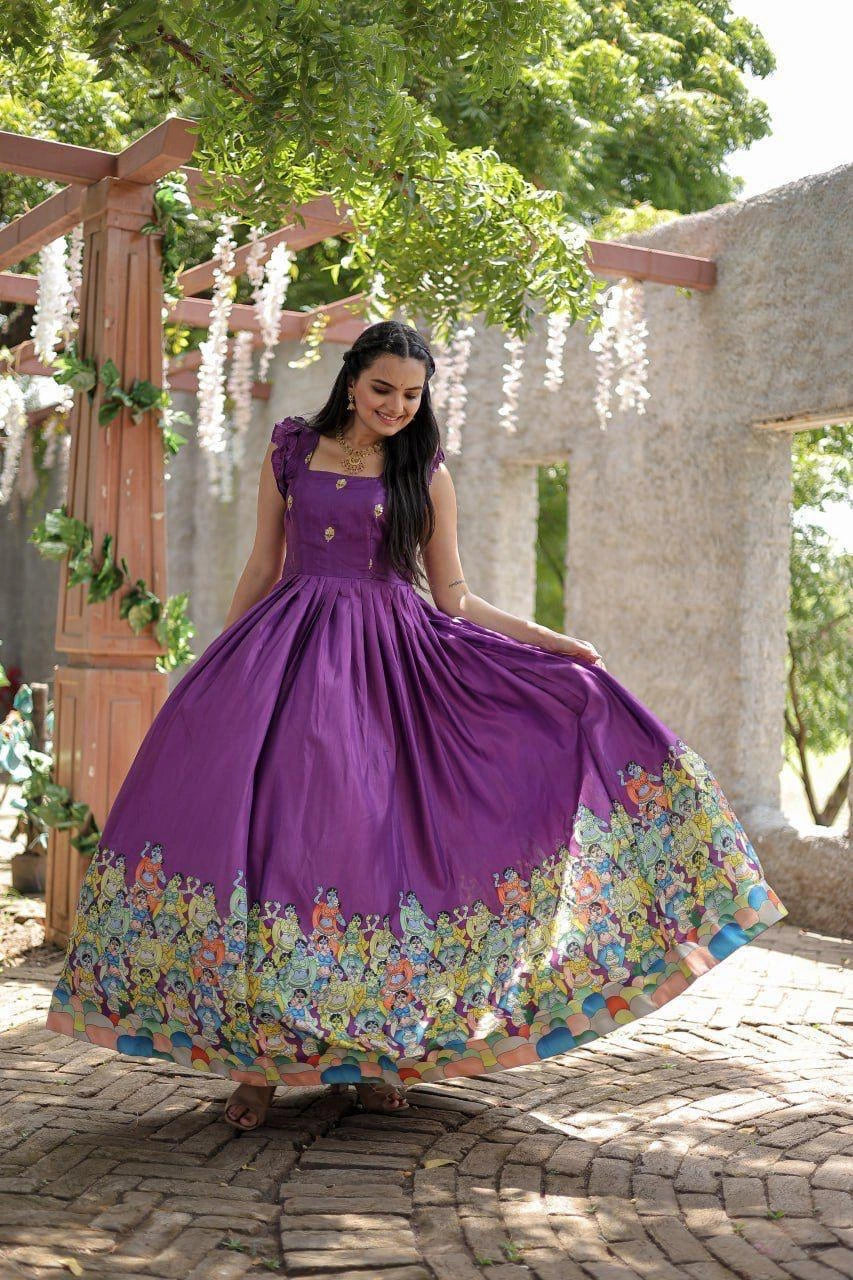 Woman in a purple dress with floral skirt standing outdoors under greenery