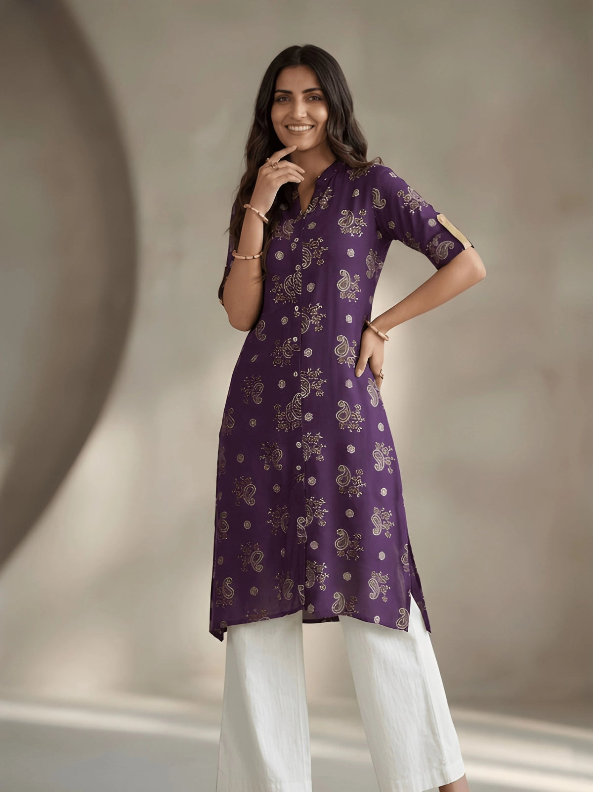 Woman wearing a purple kurta with white pants against a neutral background
