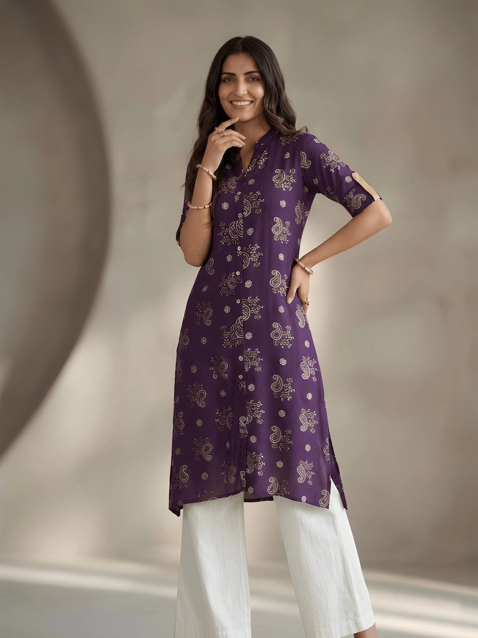 Woman wearing a purple kurta with white pants against a neutral background