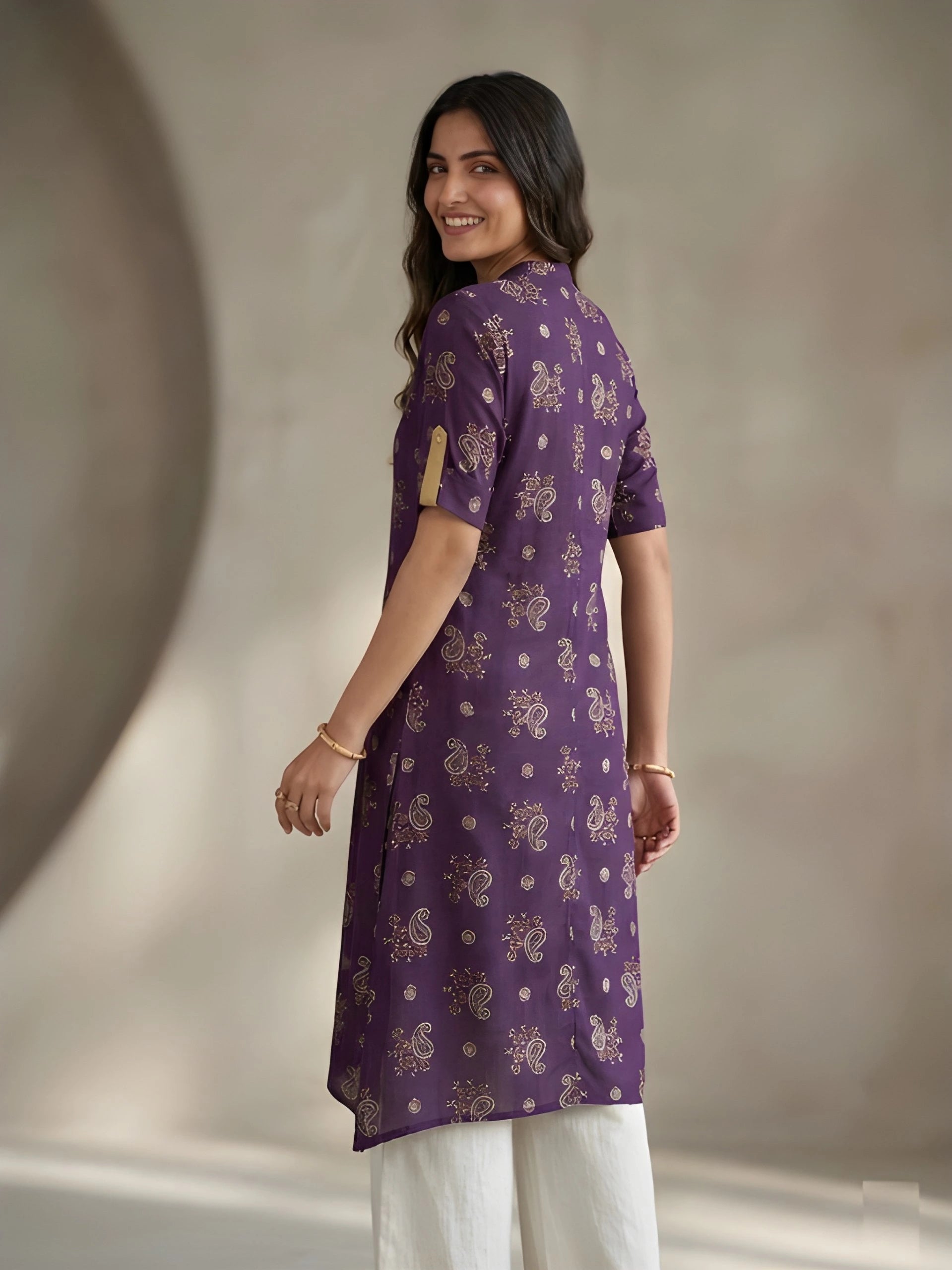 Woman wearing a purple kurta with white pants against a neutral background
