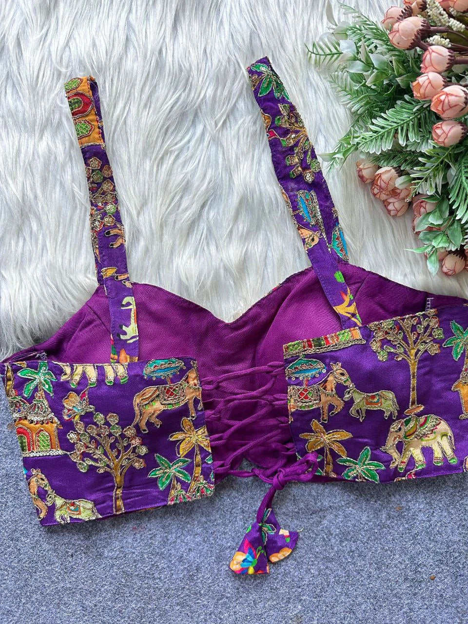 Purple traditional outfit with colorful patterns on a textured surface