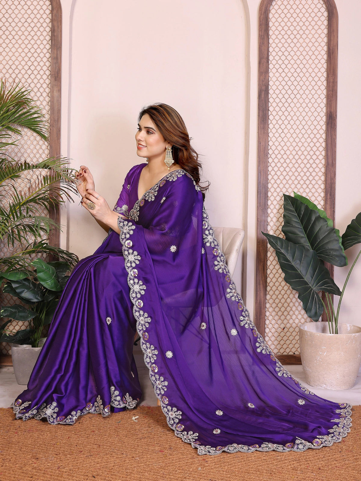 Woman wearing a purple saree with silver embroidery in an indoor setting.