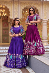 The women stand together under ornate golden arches. Both are wearing modern square sunglasses, blending contemporary styling with the traditional peacock-themed silk attire.