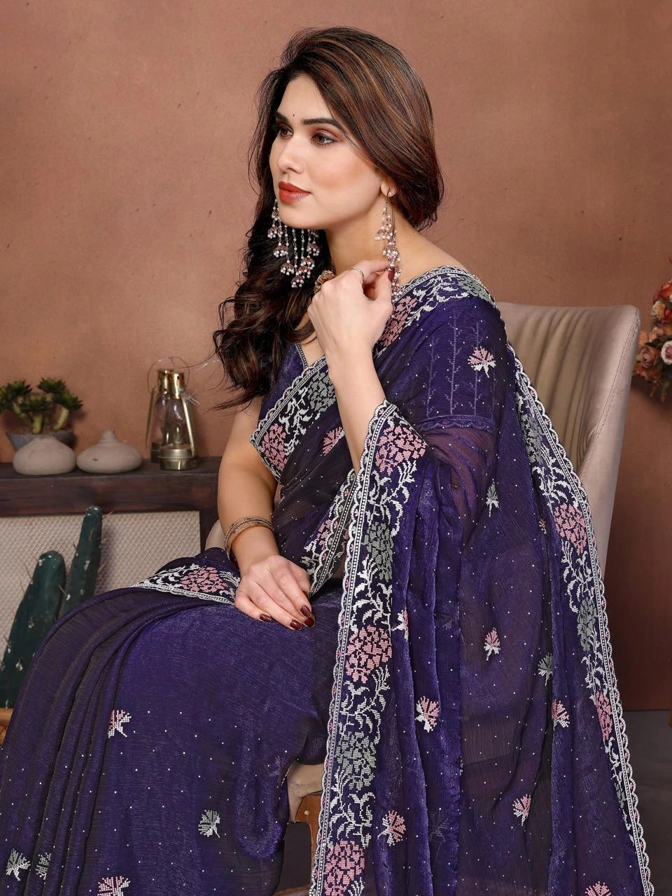 Woman wearing a purple embroidered saree with a neutral background