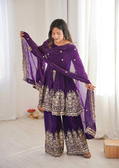 Woman wearing a purple traditional outfit with intricate designs indoors.