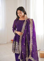 Woman wearing a purple traditional outfit with gold embroidery in a bright room.